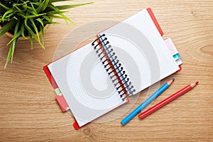 Office table with flower, blank notepad and colorful pencils