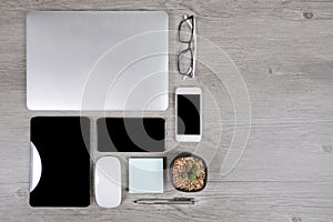 Office table with laptop computer, digital tablet, pen, smartphone, mouse, eyeglasses and coffee on white wood background