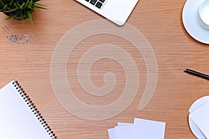 Office table with laptop, notepad and coffee cup. View from above with copy space