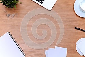 Office table with laptop, notepad and coffee cup. View from above with copy space