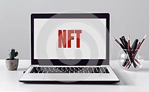 Office table and laptop with text NFT. Non-fungible token