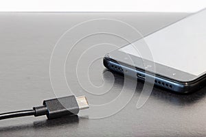 Office table mobile phone and charger jack and cord gray background surface with empty copy space for your text