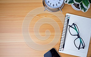 Office table of modern workplace with notebooks and pencils, phone, clock on wooden table. Top view and copy space on wooden floor