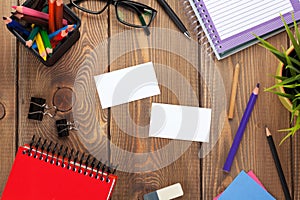 Office table with notepad, colorful pencils, supplies and business cards