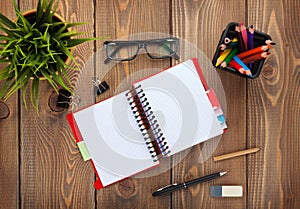 Office table with notepad, colorful pencils, supplies and flower