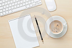 Office table with notepad, computer and coffee cup