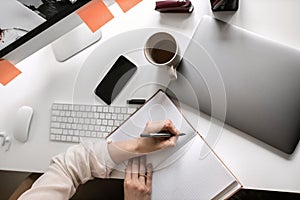 Office table with notepad, supplies, laptop, flower and coffee cup. Top view with copy space