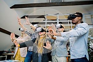 Office team of multiethnic colleagues wearing vr headset having fun together, taking part in virtual conference or