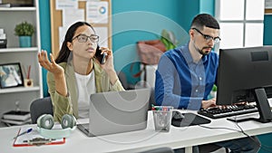 At the office, two energized workers, man and woman, actively engaging in a team meeting on a computer, briskly speaking on the