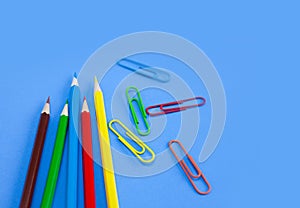 Office utensils supplies concepts, colorful pencils and clips on blue background