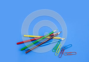 Office utensils supplies concepts, colorful pencils and clips on blue background