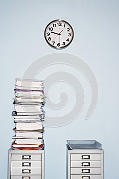 Office wall with clock stack of paperwork in inbox on file cabinet photo