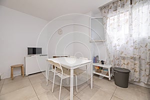 office with white wooden table and plastic chairs of the same color and window with patterned curtains