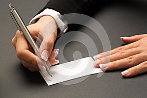 Office woman is writing with the pen on a blank white card