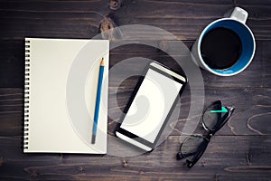 Office wood table with blank notepad, pencil, glasses and white