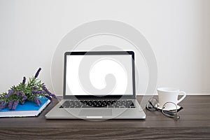 Office wood table with blank screen on notebook, coffee cup, bo