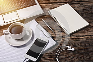 Office wooden desk with pen, notepad, coffee cup, smartphone and