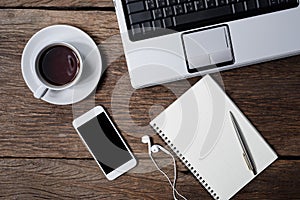Office wooden desk with pen, notepad, coffee cup, smartphone and