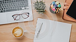 Office wooden desk workplace with laptop computer, tablet, notebook, pen and cup of coffee