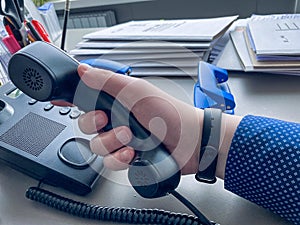 Office work. a man in a business blue shirt holds a black telephone receiver in his hands, is going to call. business