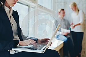 Office work process. Woman with laptop and team meeting in loft