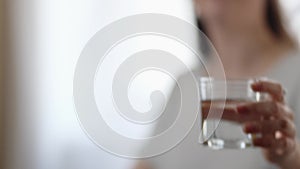 Office work. Young Caucasian woman working at laptop sitting at desktop and drinks glass of water. Close up of hands
