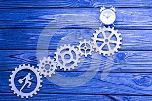 Office worker, climbs up, gears, alarm clock on a wooden background