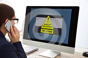 Office worker in front of computer with warning about virus attack on screen