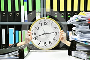 Office worker holding a clock, Working overtime and lot of work.