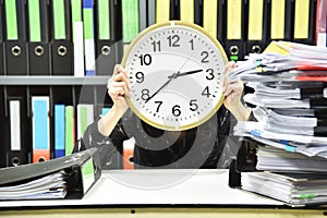 Office worker holding a clock, Working overtime and lot of work photo