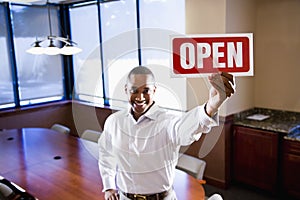 Office worker holding open sign in empty boardroom