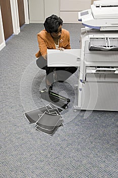 Office worker looking at photocopier photo