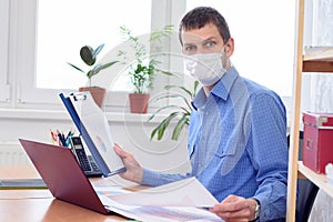 Office worker in medical mask examines data in documents with amazement