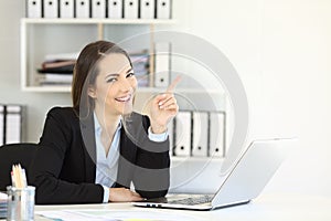 Office worker pointing at side and looking at camera