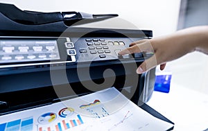 Office worker print paper on multifunction laser printer. Copy, print, scan, and fax machine in office. Modern print technology.