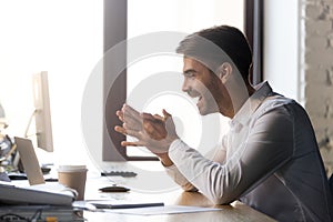 Office worker reading received message looking at computer feels happy