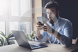 Office worker relaxing, playing online games on smartphone. Man downloading apps on his mobile device. Male checking email