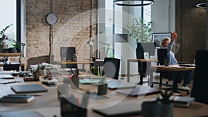 Office worker riding chair between tables in empty office. Lady having fun alone