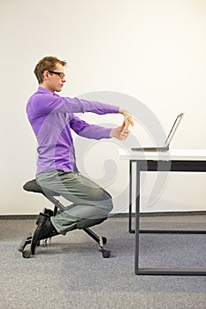 Office worker sitting on kneeling stool, exercising during short break in work