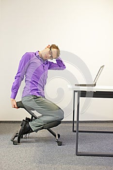 Office worker sitting on kneeling stool, stretching neck