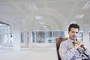 Office worker sitting in swivel chair hands clasped in empty office space photo