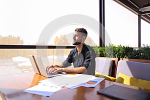 Office worker sorting papers on table near laptop.