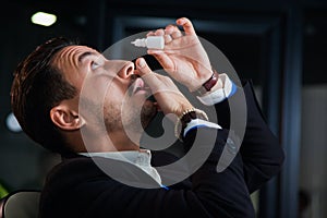 Office worker suffering dry eye syndrome, artificial tears eye drops