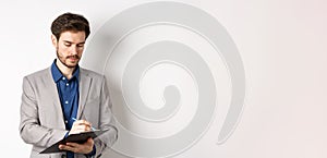 Office worker in suit writing on clipboard, taking notes on meeting, standing on white background