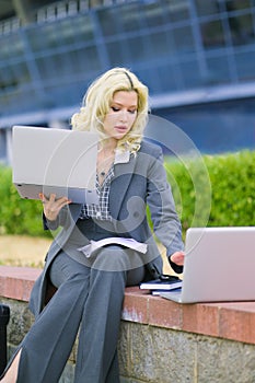 Office worker typing on two laptops outside. Business concept. Businesswoman at work