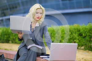 Office worker typing on two laptops outside. Business concept. Businesswoman at work