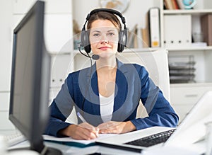 Office worker woman is working at a computer and talking by headset with client