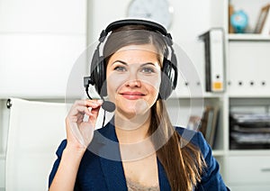 Office worker woman is working at a computer and talking by headset with client in the office