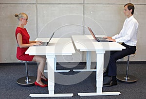 Office workers in correct sitting posture at desks with laptops