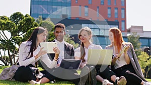 Office workers multiracial one guy and women team have a great day working in the business centre park down on the grass